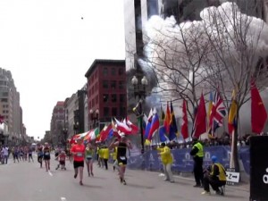 Runners prepare to cross the finish line as the first explosion occurs