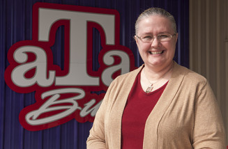 Anne Smith stands by the aTa Bus logo. Smith has been the director of the aTa Bus since 2007. (Courtesy photo)
