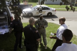 Capt. David L. Robinson (center), 162nd EOD Co., 84th EOD Bn., 1st Sust. Bde., 1st Inf. Div., discusses the recovery and relocation of an unexploded ordnance unearthed June 20 near the intersection of Jackson Avenue and Hampton Place at Fort Riley with members of the post's Directorate of Emergency Services. The UXO was removed safely and without incident. (U.S. Army photo) 