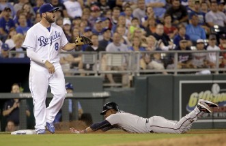 Minnesota Twins' Eduardo Escobar slides in with an RBI triple as Kansas City Royals third baseman Mike Moustakas waits for the ball during the ninth inning of a baseball game against the Kansas City Royals Thursday, July 2, 2015, in Kansas City, Mo. (AP Photo/Charlie Riedel)