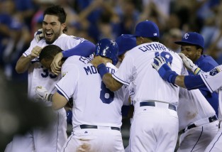 Kansas City Royals' Eric Hosmer, left, mobs teammate Alcides Escobar with Mike Moustakas (8) and Cheslor Cuthbert (19) following his game-winning hit during the tenth inning of a baseball game against the Houston Astros at Kauffman Stadium in Kansas City, Mo., Saturday, July 25, 2015. The Royals defeated the Astros 2-1 in ten innings. (AP Photo/Orlin Wagner)