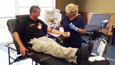 Manhattan Fire Department Battalion Chief Mark Whitehair finishes up his blood donation Tuesday at St Thomas More Catholic Church.
