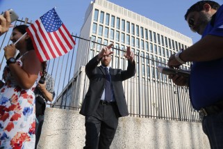 An employee of the United States Embassy Havana asks pedestrians to move back and away from the embassy gates, Monday, July 20, 2015. The U.S. Interests Section in Havana plans to announce its upgrade to embassy status in a written statement on Monday, but the Stars and Stripes will not fly at the mission until Secretary of State John Kerry visits in August for a ceremonial flag-raising. (AP Photo/Desmond Boylan)