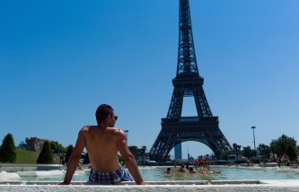 A man relaxes by the fountain of the Trocadero gardens, in front of the Eiffel Tower, in Paris, Wednesday, July 1, 2015. A mass of hot air moving north from Africa has driven up temperatures in Spain, Portugal, Britain and France in recent days. Temperatures in Paris were expected to hit 39 degrees Celsius (102 Fahrenheit) Wednesday afternoon. (AP Photo/Thibault Camus)