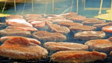 SIZZLING: Pork burgers cook on an open grill Friday afternoon at the Riley County Fairground in Manhattan. Friday night was the fair's annual pork burger feed prepared by the Blue Valley Pork Producers. (Staff photo by Brady Bauman)