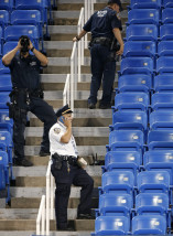 Police officers investigate the southwest corner of Louis Armstrong Stadium after a drone flew over the court, buzzing the players during a match between Flavia Pennetta, of Italy, and Monica Niculescu, of Romania, during the second round of the U.S. Open tennis tournament in New York, Thursday, Sept. 3, 2015. The drone crash-landed in the seats and can be seen to the right of the police officer on his phone. (AP Photo/Kathy Willens)