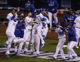 Kansas City Royals players celebrate after Alcides Escobar scored on a sacrifice fly by Eric Hosmer during the 14th inning of Game 1 of the Major League Baseball World Series against the New York Mets Wednesday, Oct. 28, 2015, in Kansas City, Mo.  (AP Photo/Orlin Wagner)