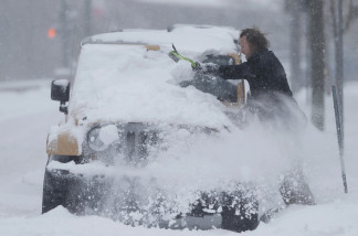 An unidentified motorist clears snow off his four-wheel-drive vehicle in high winds early Tuesday, Dec.15, 2015, in Denver. Forecasters predict that four to 10 inches of snow will blanket Colorado's eastern plains before the storm, which started Monday in the intermountain West, moves to the east. (AP Photo/David Zalubowski)
