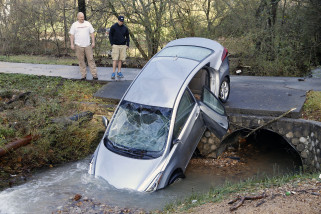 Tanager Tyler and son Mitchell look over a vehicle, Saturday, Dec. 26, 2015, that wound up in the culvert of their driveway after floodwaters swept it and its four occupants off the road during the previous night, in Pinson, Ala. The occupants had to be rescued by the fire department. (AP Photo/ Hal Yeager)