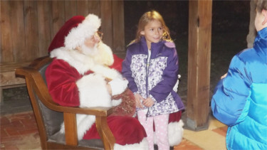 Sarah Tychnowitz of Manhattan poses for a picture while on Santa's lap in Triangle Park Friday night.