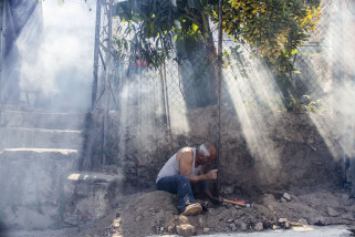 A man works on a fence amidst a cloud of insecticide as city workers fumigate to combat the Aedes Aegypti mosquitoes that transmits the Zika virus, at the San Judas Community in San Salvador, El Salvador, Tuesday, Jan. 26, 2016.  Worries about the rapid spread of Zika through the hemisphere has prompted officials in El Salvador, Colombia and Brazil to suggest women stop getting pregnant until the crisis has passed. (AP Photo/Salvador Melendez)