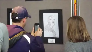 A passerby snaps a photo of one of the MLK art pieces Monday in the Manhattan Town Center. Art and poems created by elementary school students were displayed. (Staff photos by Brady Bauman)