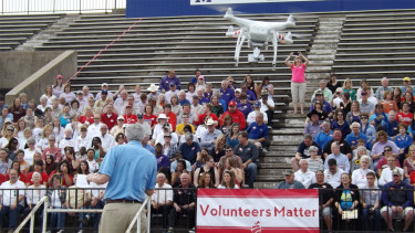 A drone joins Manhattan Area Chamber of Commerce President Lyle Butler in addressing the crowd at Bishop Stadium in Manhattan. 