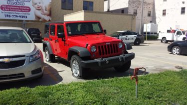 A Jeep sits lopsided Thursday morning after several vehicles were found with slashed tires in a parking lot in downtown Manhattan. (Staff photo by Brady Bauman)