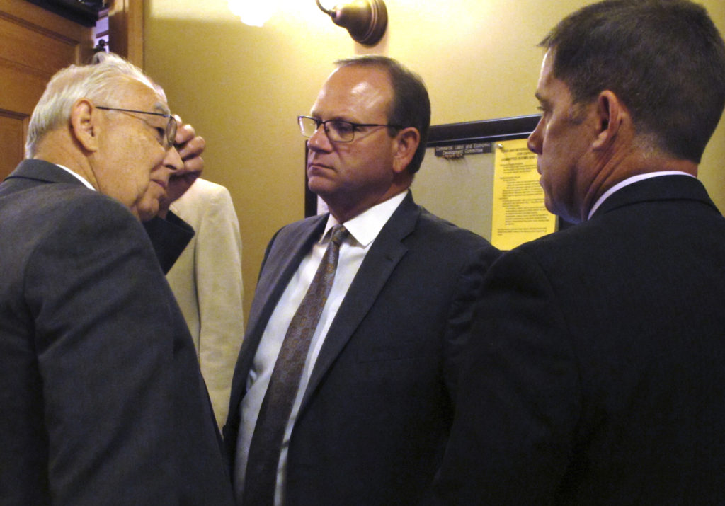 Deputy Kansas Education Commissioner Dale Dennis, left, confers with Superintendents Todd White, center, and Jim Hinson, right, of the Blue Valley and Shawnee Mission school districts from Johnson County, Kansas, as legislators review school funding issues, Thursday, June 23, 2016, at the Statehouse in Topeka, Kan. The Blue Valley and Shawnee Mission districts stand to lose nearly $3.9 million in state aid under a plan drafted by Republican legislators. (AP Photo/John Hanna)