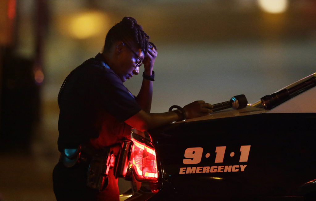 A Dallas police officer, who did not want to be identified, takes a moment as she guards an intersection in the early morning after a shooting in downtown Dallas, Friday, July 8, 2016. At least two snipers opened fire on police officers during protests in Dallas on Thursday night; some of the officers were killed, police said. (AP Photo/LM Otero)